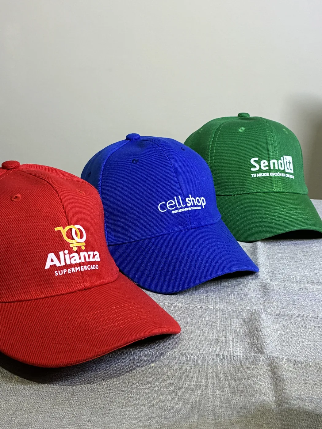 Kepis personalizados rojo, azul y verde con logos de empresas paraguayas
